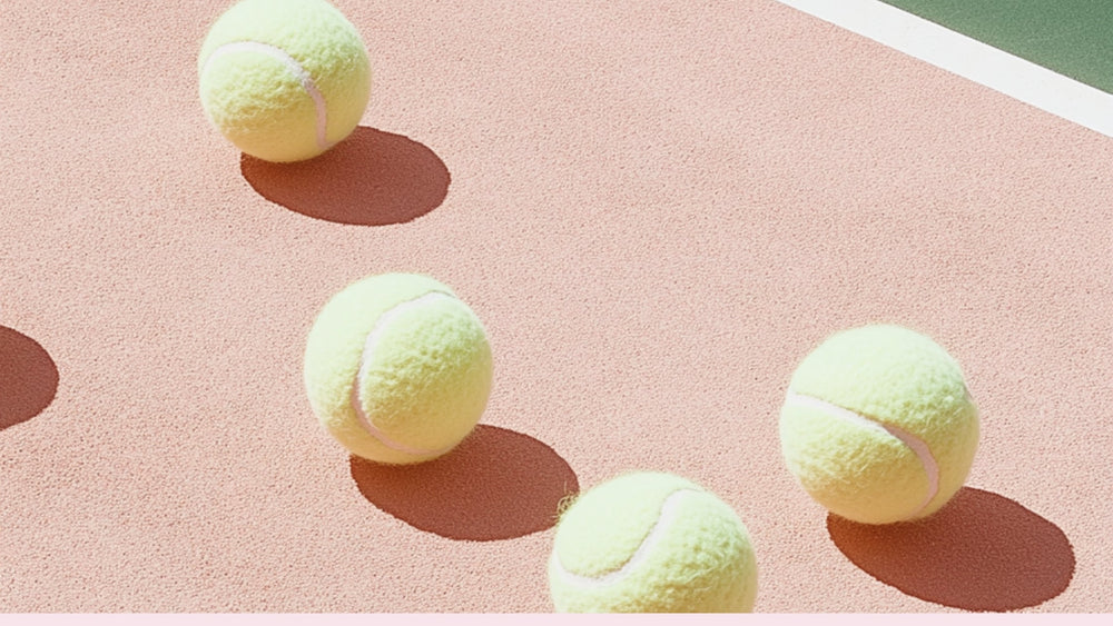 four tennis balls on a pink hardcourt tennis court