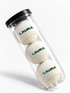 Mockup of three white tennis balls personalised with LAURA in green, in a clear tube with a black lid.