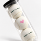 Mockup of three white tennis balls in a clear tube, with green FORTY-LOVE on two balls and a pink heart on the middle ball.