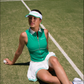 Courtside lifestyle image of a women’s tennis look with a fitted green tank top and white skort, styled for performance and style.