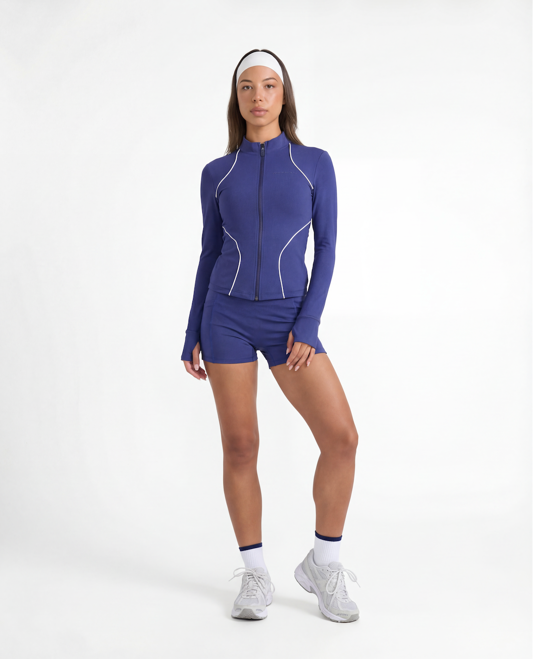 Studio lifestyle image of a navy women’s tennis jacket styled as a complete long sleeve tennis outfit.