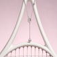 Silver lariat necklace with a tennis racquet charm and ball drops, hanging from a white racquet frame against pink