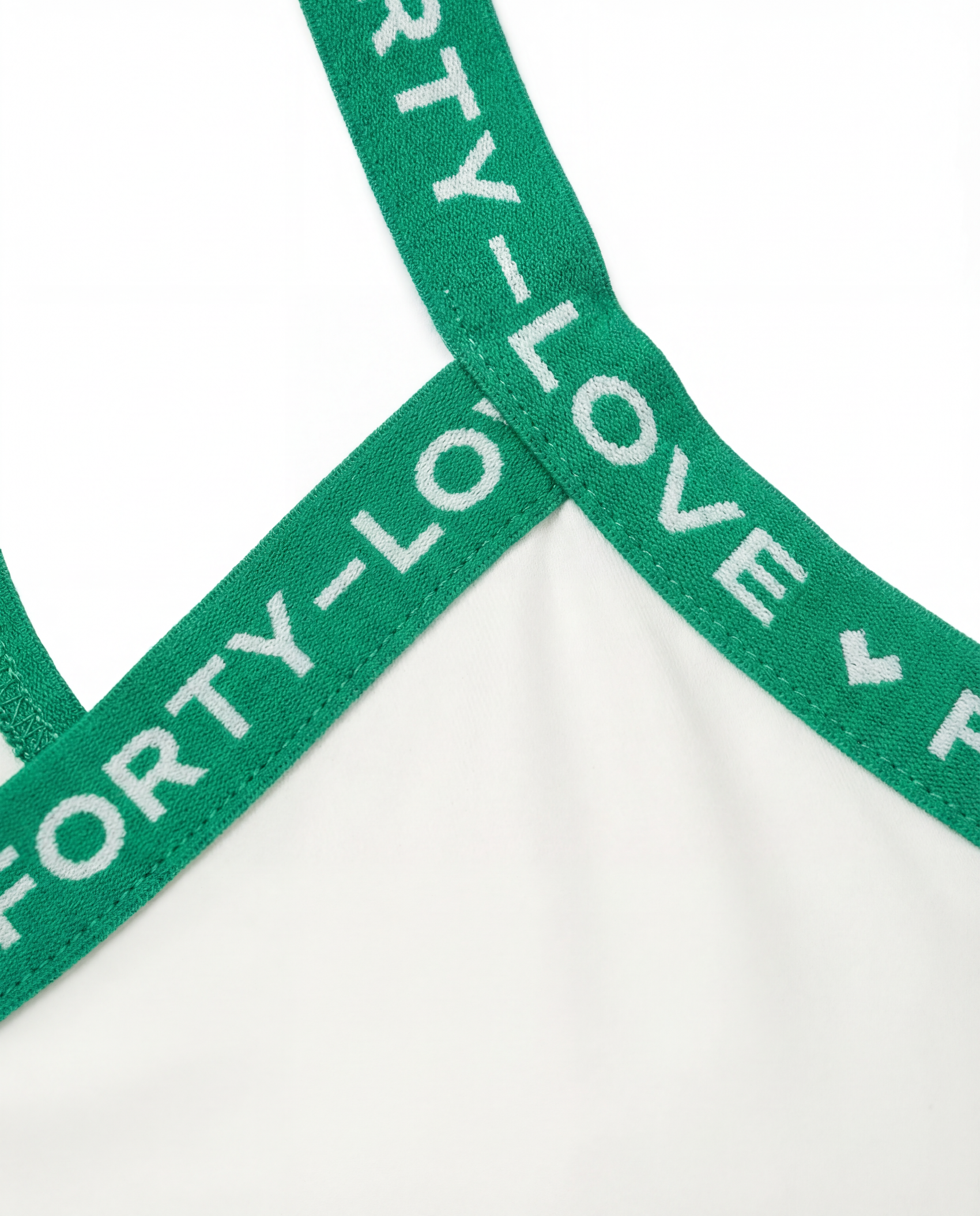 Close-up detail of branded elastic strap on a women’s tennis tank top, highlighting premium finish and stretch support.