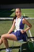 Model wearing a navy and white women’s tennis dress seated courtside, featuring a pleated skirt and zip-front design.