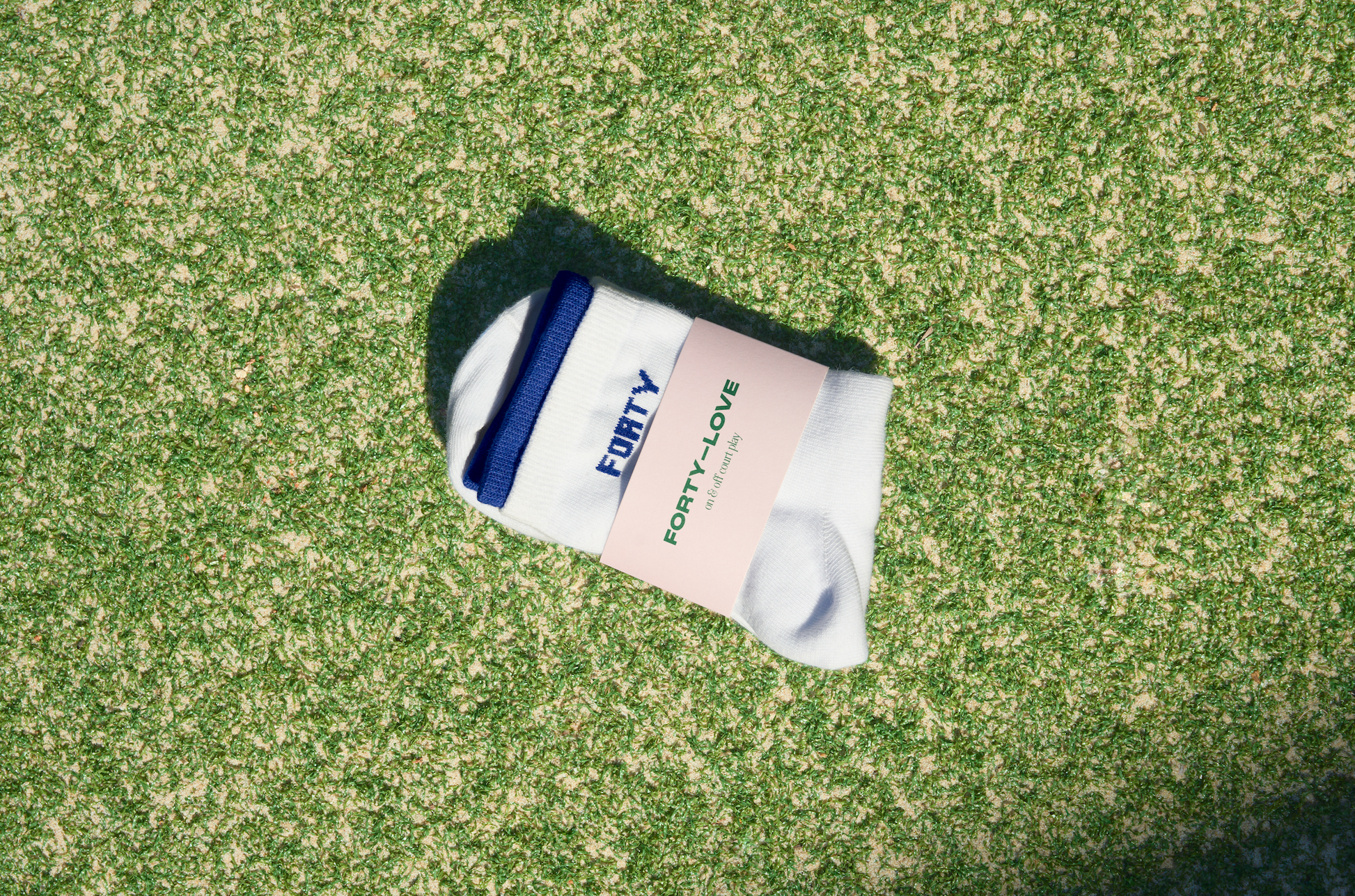 White and navy womens tennis socks by Forty-Love folded on a tennis court, designed for comfort and on-court performance.